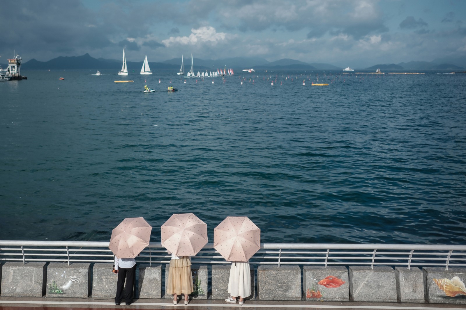 看 海-2023年6月20日，深圳南澳海邊，烈日下，游客打傘看海，遠(yuǎn)處是在為端午舉辦龍舟賽正在進(jìn)行訓(xùn)練的賽手們。-薛云麾.jpg